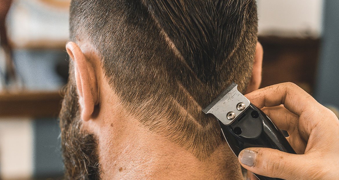 Profissional faz o corte degradê em V no cabelo longo de seu cliente